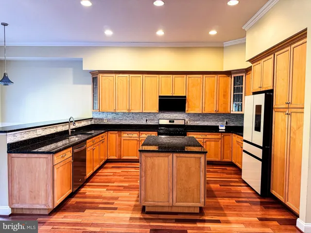 a kitchen with stainless steel appliances granite countertop a stove a sink and a refrigerator with wooden floors