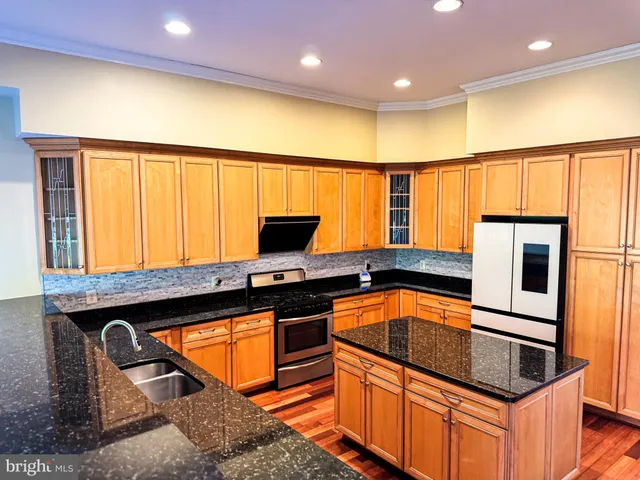 a view of kitchen with stainless steel appliances wooden floor and a window