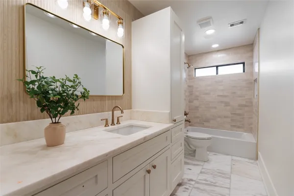 a bathroom with a sink a toilet and a large mirror
