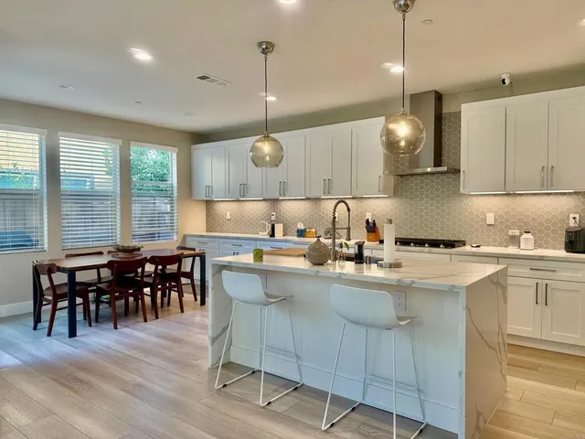 a kitchen with a dining table chairs sink and wooden floor