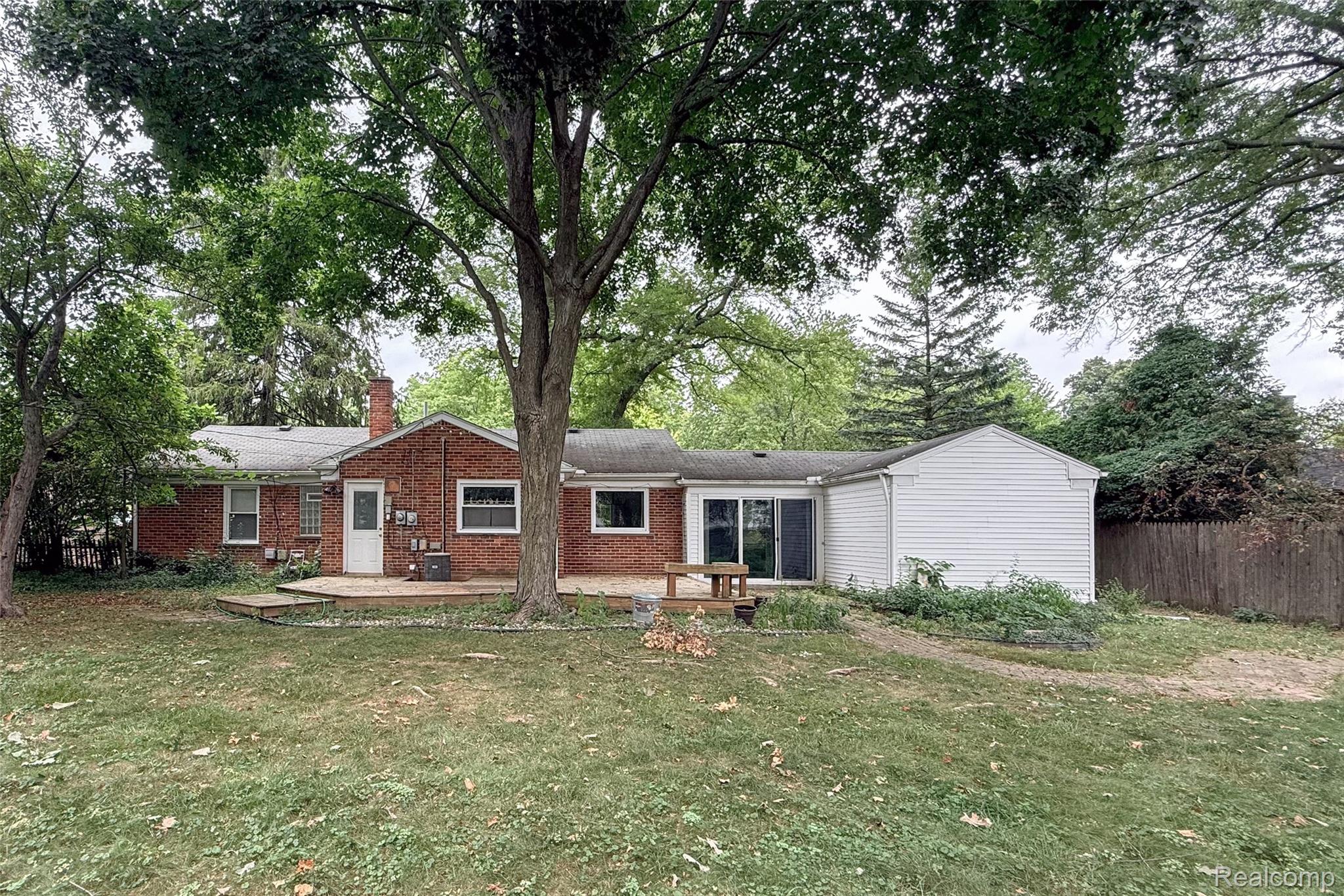 1846 Pembroke Road Birmingham, MI 48009 - Photo 6 of 37 Brick exterior with white trim, wood deck, sliding glass door, and expansive green lawn