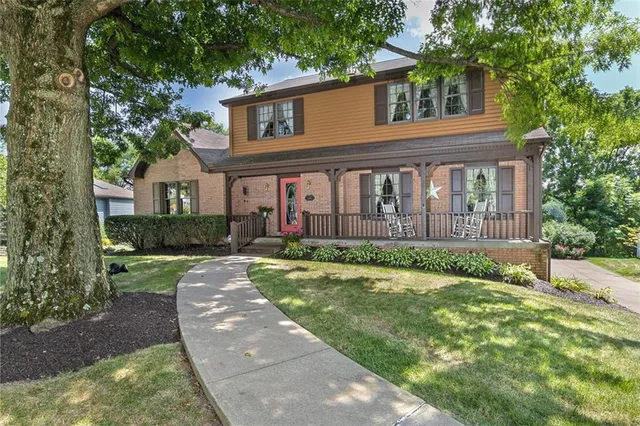 a view of a white house with a large windows and a big yard and large trees