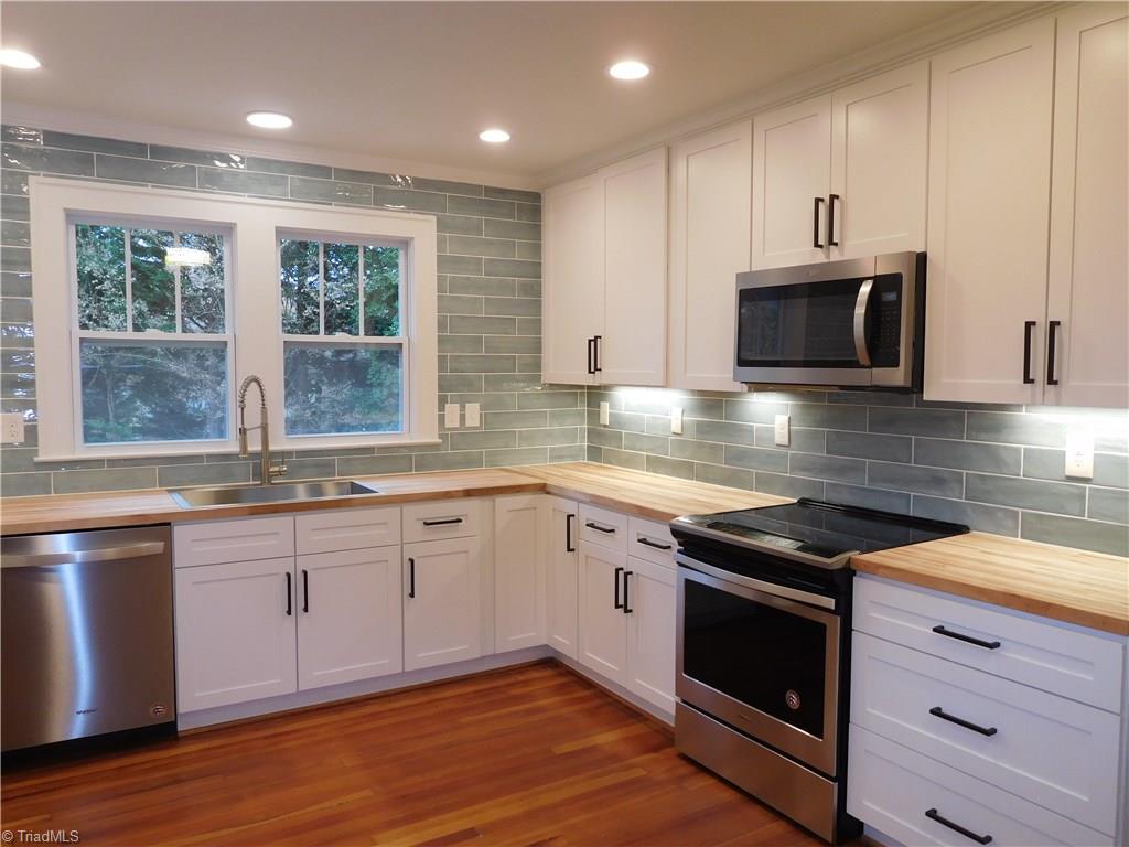 2402 Polo Road Winston-Salem, NC 27106 - Photo 11 of 30 White shaker cabinets w/black pulls, Tile backsplash, butcher block counter-tops, under cabinet lights and All NEW Stainless Steel appliances.