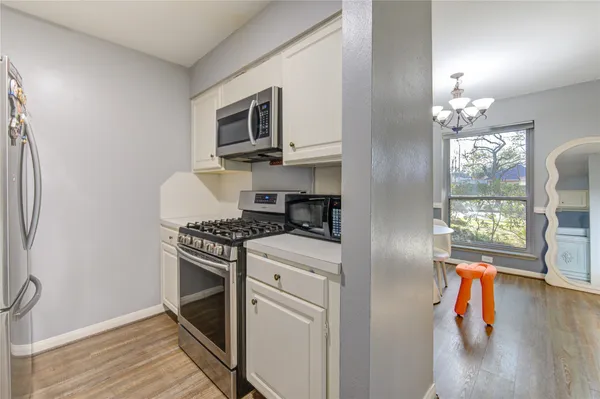 a kitchen with stainless steel appliances granite countertop a refrigerator a stove a sink dishwasher and white cabinets with wooden floor