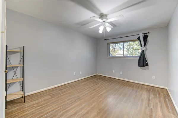 an empty room with wooden floor fan and windows