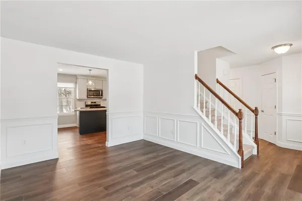 a view of a hallway with wooden floor and a kitchen