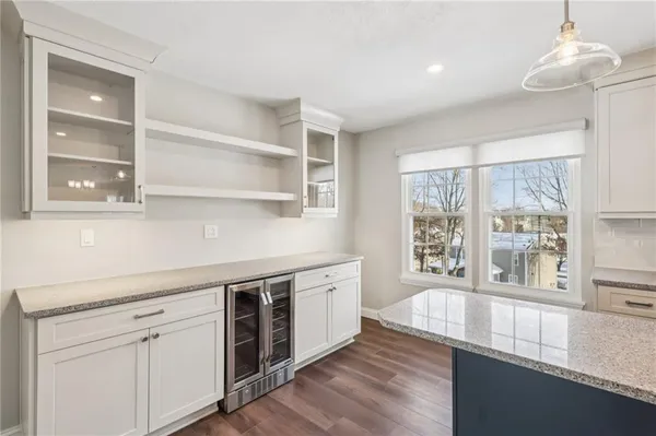 a open kitchen with stainless steel appliances granite countertop a stove a sink and white cabinets with wooden floor next to windows