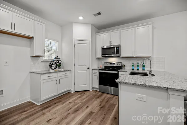 a kitchen with granite countertop white cabinets and stainless steel appliances