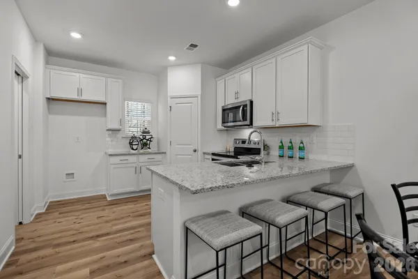 a kitchen with stainless steel appliances granite countertop a stove a sink and white cabinets