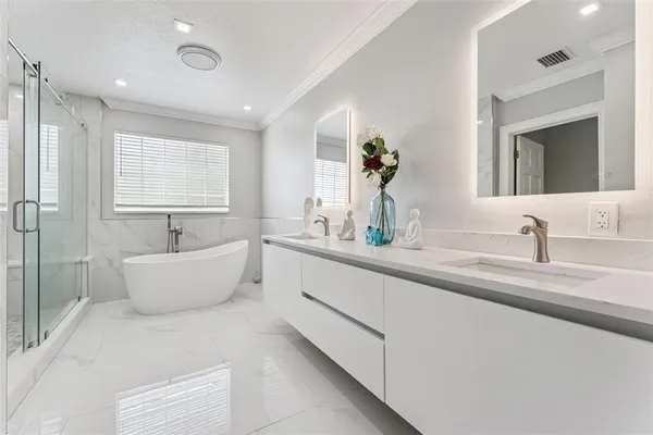 a bathroom with a double vanity sink a mirror and a bathtub