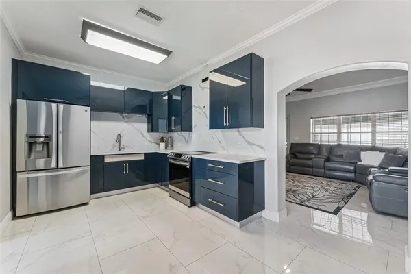 a large white kitchen with stainless steel appliances kitchen island granite countertop a refrigerator and a stove top oven