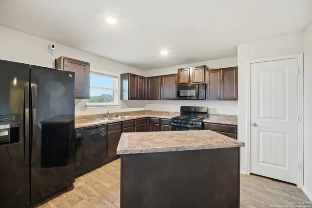 a kitchen with granite countertop a refrigerator and a stove top oven
