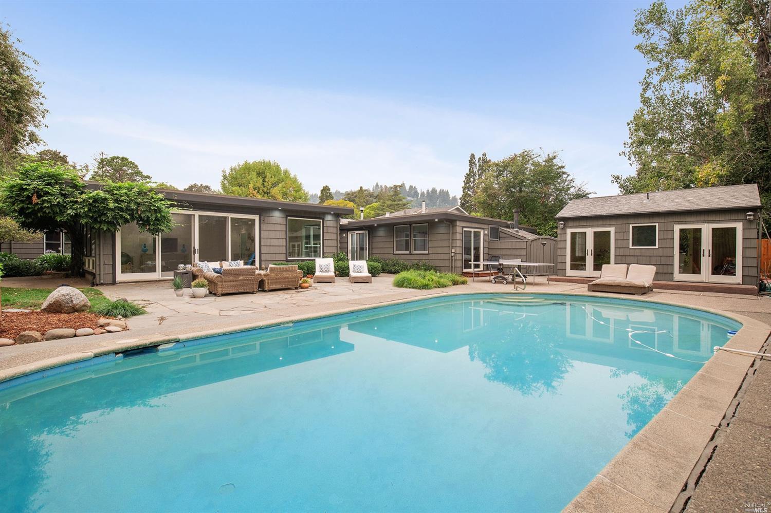 a swimming pool view with a seating space and a garden view