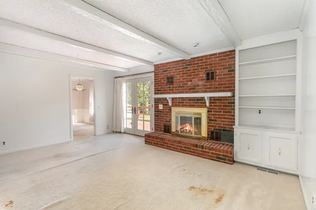 a view of an empty room with a fireplace and a window