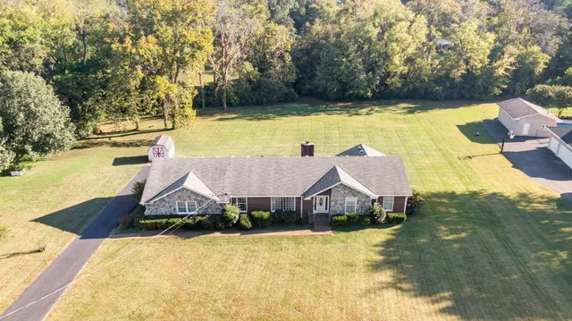 a aerial view of a house with swimming pool and large trees
