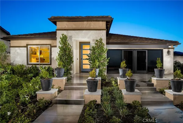 a view of a house with potted plants and a table and chairs