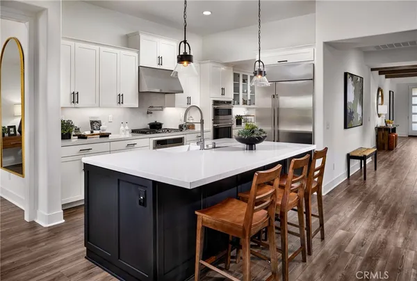 a kitchen with stainless steel appliances kitchen island a table chairs in it and wooden floors