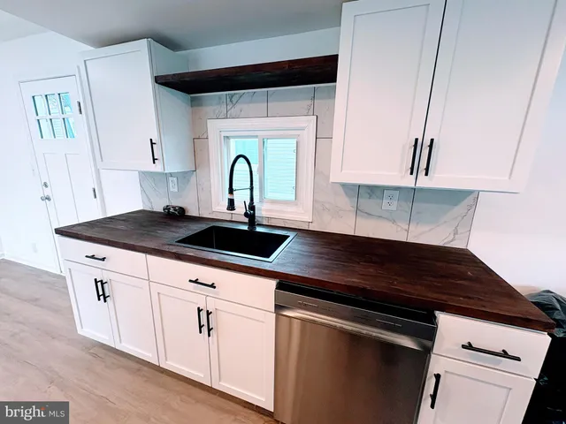 a kitchen with granite countertop a sink cabinets and stainless steel appliances