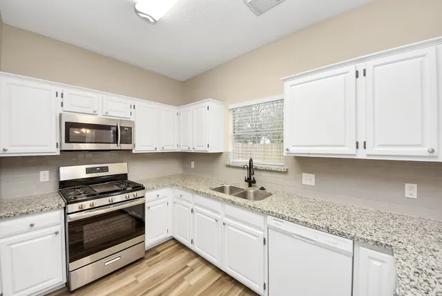 a kitchen with granite countertop white cabinets and appliances