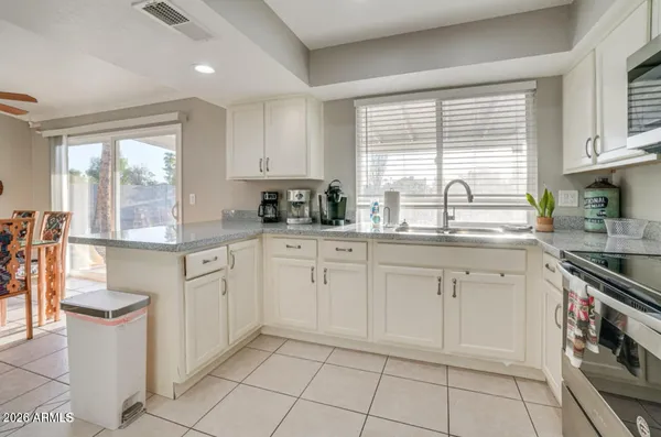 a kitchen with white cabinets a sink a stove a window and cabinetry