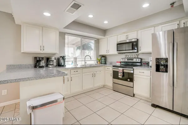 a kitchen with white cabinets stainless steel appliances a sink and a counter top space