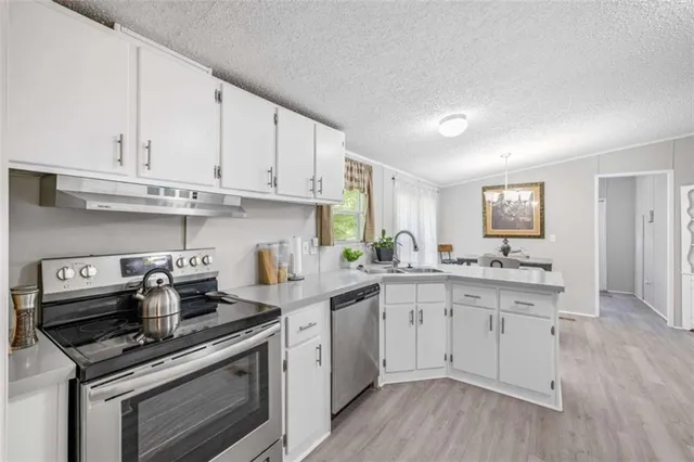 a kitchen with stainless steel appliances white cabinets and a stove top oven