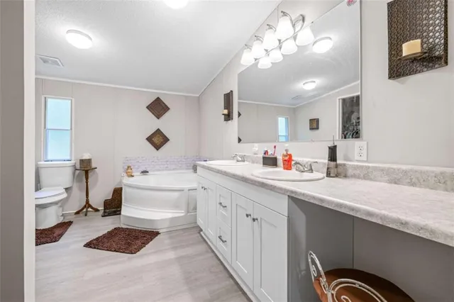 a spacious bathroom with a double vanity sink a toilet and a mirror