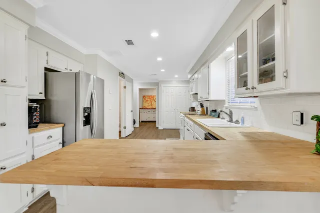 a large white kitchen with kitchen island a sink stainless steel appliances and cabinets