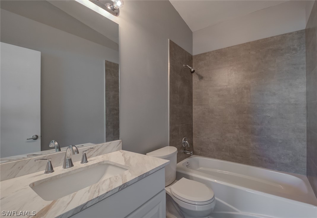 18485 Sebring Road Fort Myers, FL 33967 - Photo 13 of 21 a bathroom with a granite countertop sink toilet a mirror and a bathtub