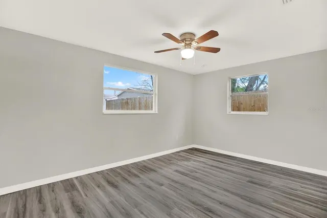 a view of an empty room with wooden floor and window