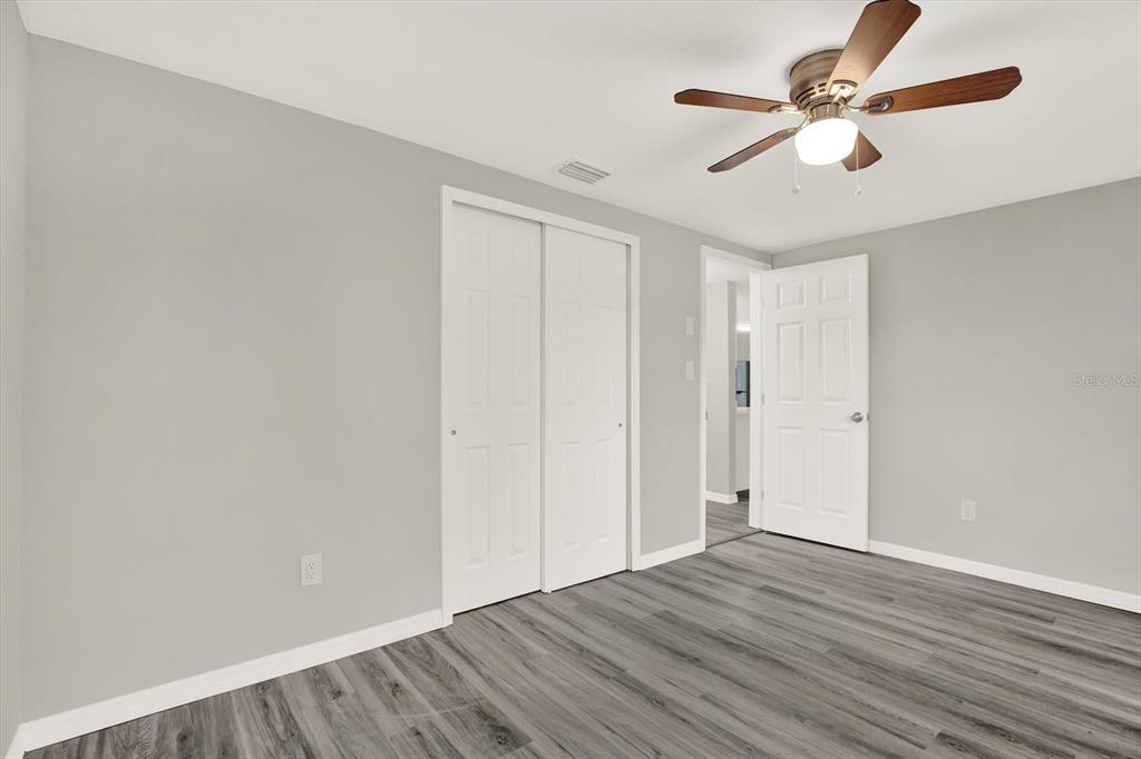 5038 Galaxy Drive New Port Richey, FL 34652 - Photo 13 of 32 an empty room with wooden floor ceiling fan and window