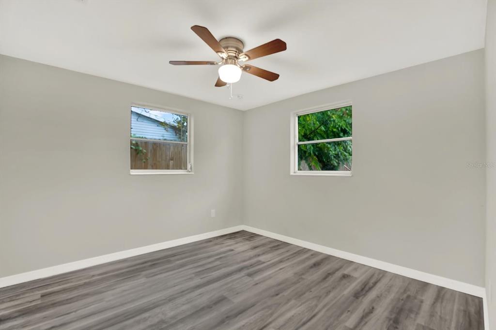 5038 Galaxy Drive New Port Richey, FL 34652 - Photo 14 of 32 a view of an empty room with wooden floor and a ceiling fan