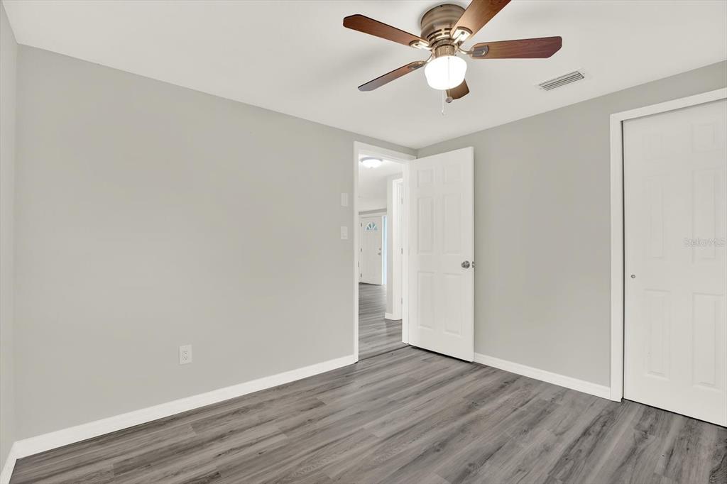 5038 Galaxy Drive New Port Richey, FL 34652 - Photo 15 of 32 an empty room with wooden floor ceiling fan and window