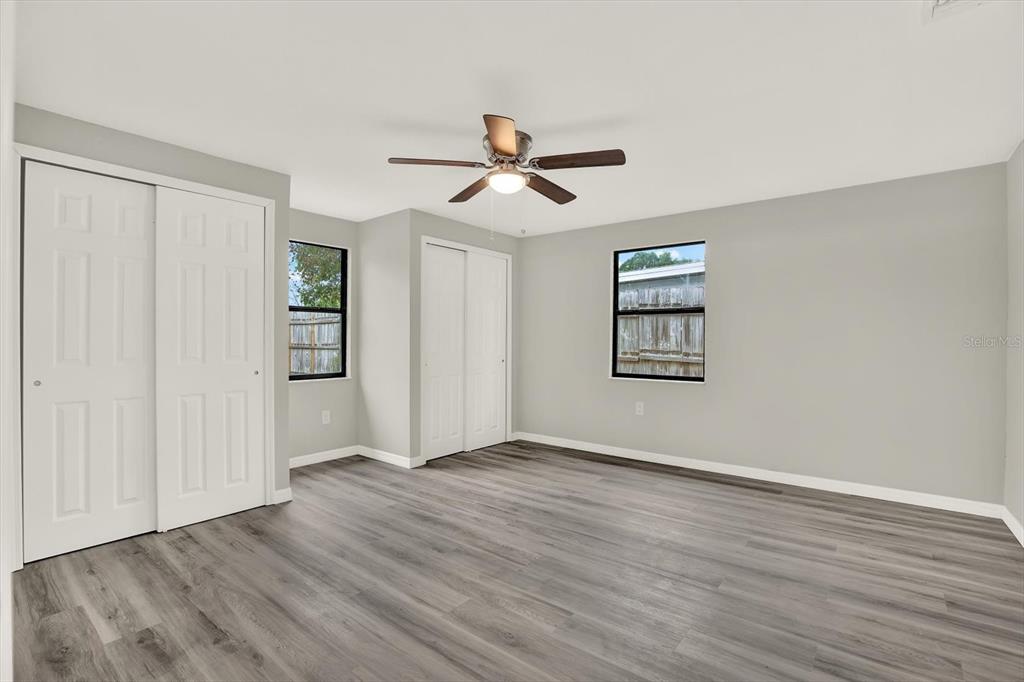 5038 Galaxy Drive New Port Richey, FL 34652 - Photo 17 of 32 an empty room with wooden floor ceiling fan and windows