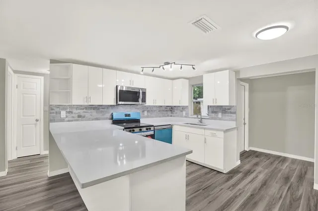 a kitchen with granite countertop a sink cabinets and wooden floor