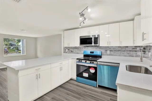 a kitchen with cabinets stainless steel appliances and wooden floor