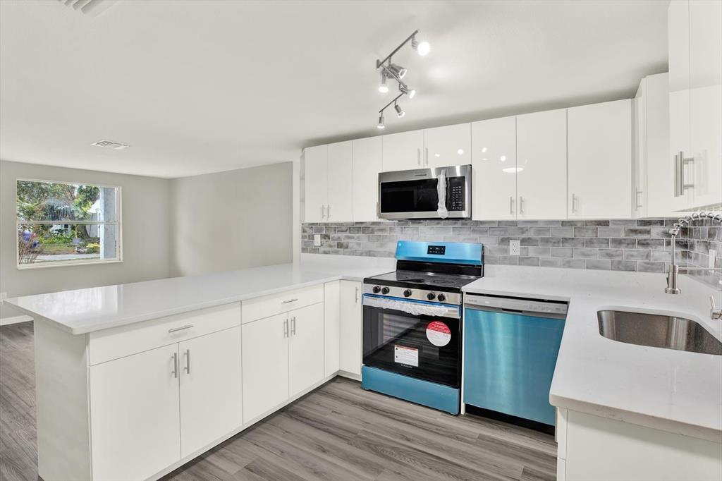 5038 Galaxy Drive New Port Richey, FL 34652 - Photo 5 of 32 a kitchen with cabinets stainless steel appliances and wooden floor
