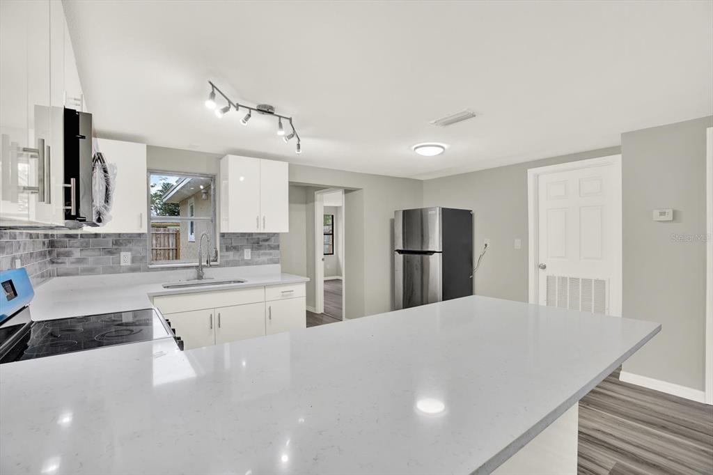 5038 Galaxy Drive New Port Richey, FL 34652 - Photo 6 of 32 a large white kitchen with kitchen island a sink stainless steel appliances and cabinets