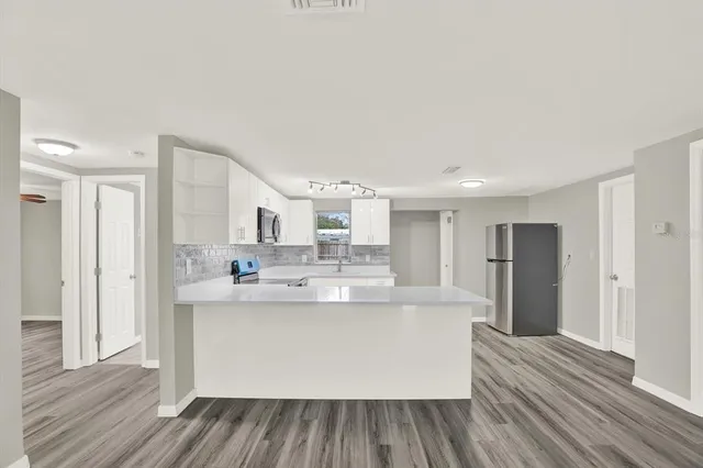 a large kitchen with stainless steel appliances a large counter top a stove and a refrigerator