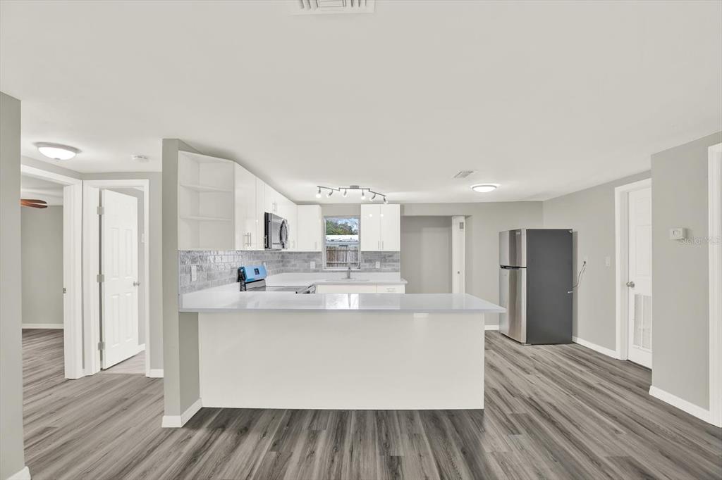 5038 Galaxy Drive New Port Richey, FL 34652 - Photo 8 of 32 a large kitchen with stainless steel appliances a large counter top a stove and a refrigerator