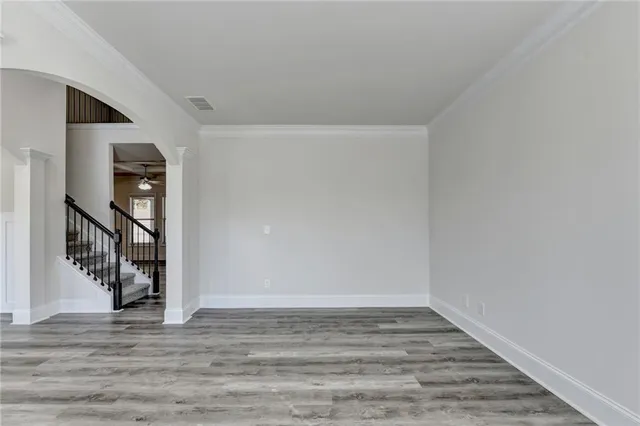 a view of an empty room with wooden floor and stairs