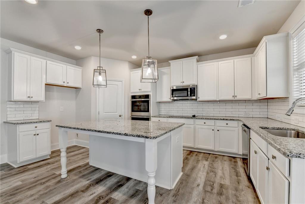 1661 Silver Crest Way Hoschton, GA 30548 - Photo 24 of 57 a kitchen with granite countertop white cabinets white appliances and granite counter tops