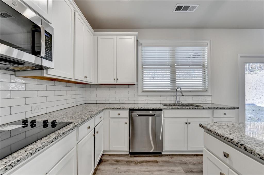 1661 Silver Crest Way Hoschton, GA 30548 - Photo 26 of 57 a kitchen with stainless steel appliances granite countertop a sink a stove and cabinets