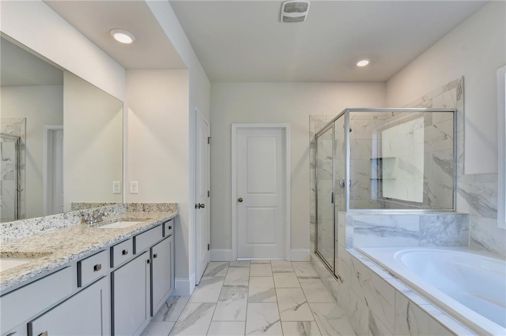 1661 Silver Crest Way Hoschton, GA 30548 - Photo 49 of 57 a spacious bathroom with a granite countertop sink a toilet a mirror and shower