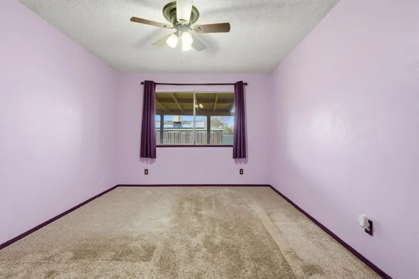 an empty room with a window and a ceiling fan
