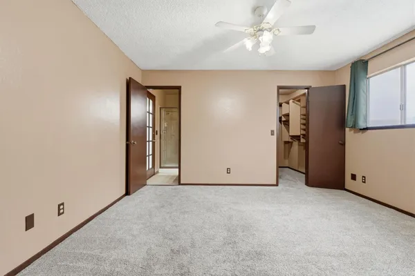 an empty room with closet and a chandelier fan