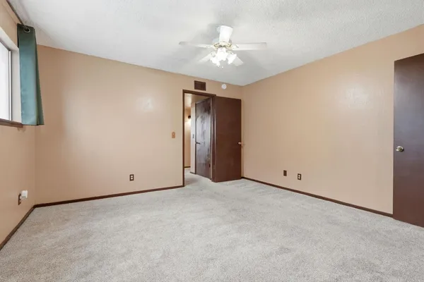 an empty room with a chandelier fan and windows