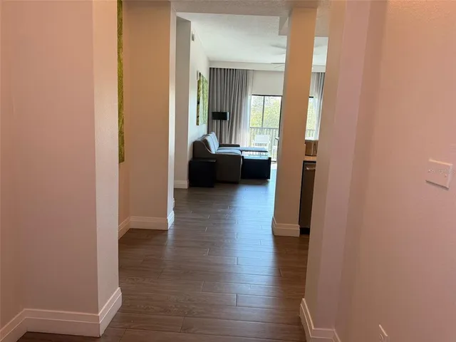 a view of a hallway with wooden floor and a living room