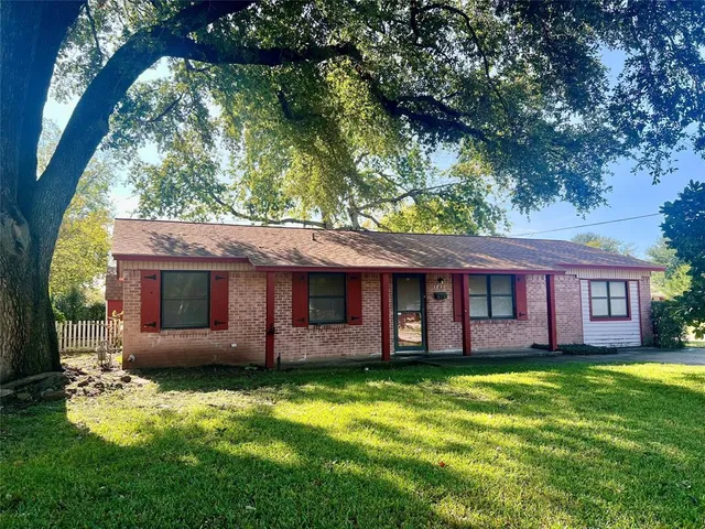 a view of a house with a yard and large tree