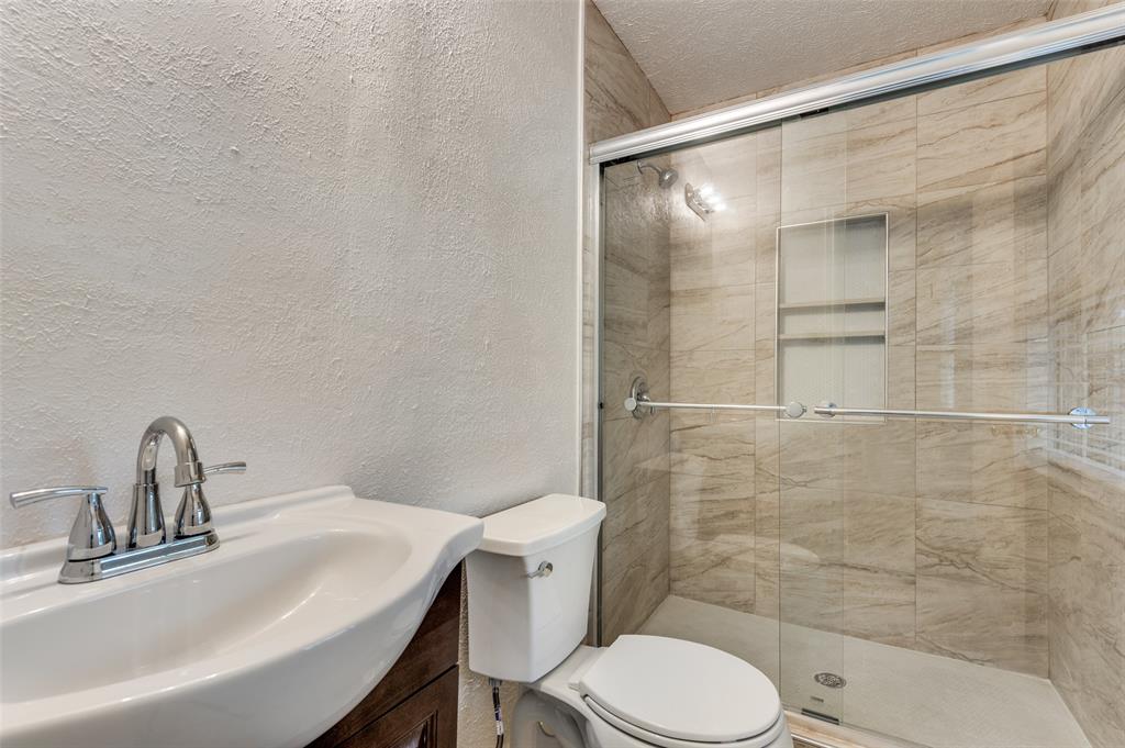 1230 Fairdale Street Irving, TX 75062 - Photo 21 of 24 Bathroom with a textured wall, vanity, a stall shower, and a textured ceiling